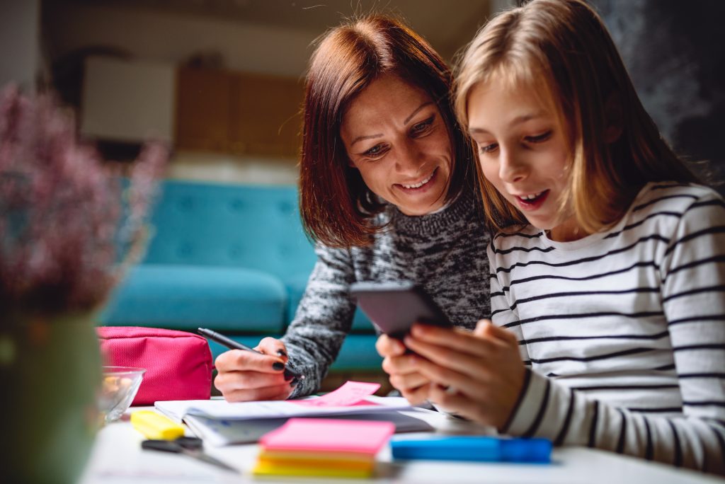 Nottingham fostering family. Single mum and foster child on a smartphone together at home.